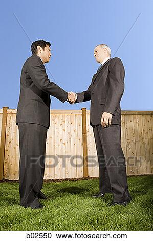 Low angle view of two businessmen shaking hands View Large Photo Image Stock Image - Low angle view of two businessmen shaking hands. Fotosearch