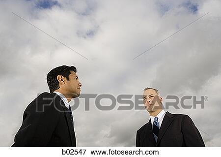 Low angle view of two businessmen standing View Large Photo Image Stock Photo - Low angle view of two businessmen standing. Fotosearch