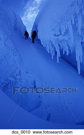 Stock Image - Low angle view of two people hiking through snow covered terrain. Fotosearch