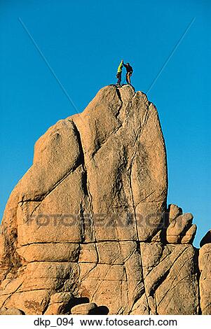 Picture - Low angle view of two people standing on top of a mountain. Fotosearch