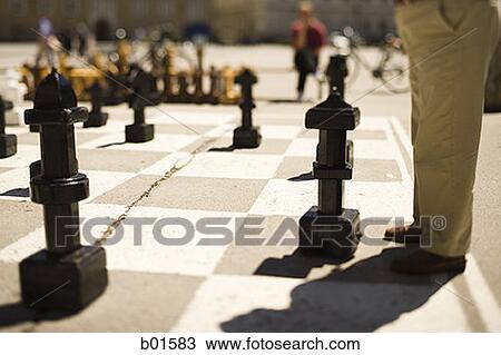 Stock Image - Low section view of a man playing oversized outdoor chess. Fotosearch