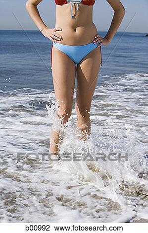 Low section view of a young woman standing in water on the beach View Large Photo Image Stock Image - Low section view of a young woman standing in water on the beach. Fotosearch