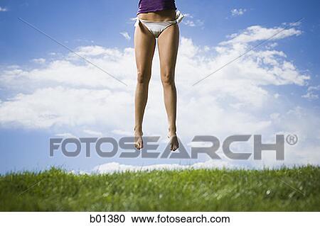 Low section view of a young woman jumping in a garden View Large Photo Image Stock Image - Low section view of a young woman jumping in a garden. Fotosearch