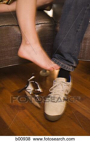 Low section view of a young woman's foot touching a young man's ankle View Large Photo Image Stock Photo - Low section view of a young woman's foot touching a young man's ankle. Fotosearch