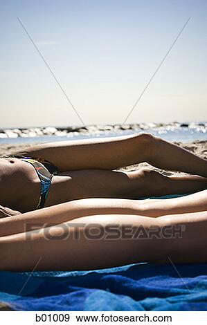 Low section view of two young women sunbathing on the beach View Large Photo Image Stock Photo - Low section view of two young women sunbathing on the beach. Fotosearch