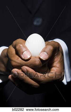 Stock Image - Man holding an egg. Fotosearch