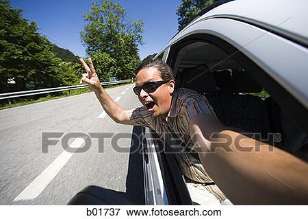 Mid adult man leaning out of a moving car View Large Photo Image Stock Photo - Mid adult man leaning out of a moving car. Fotosearch