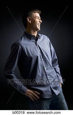 Stock Photo - Mid adult man standing with his hands on his hips. Fotosearch