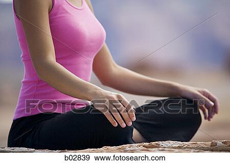 Mid section view of a young woman meditating View Large Photo Image Stock Photo - Mid section view of a young woman meditating. Fotosearch