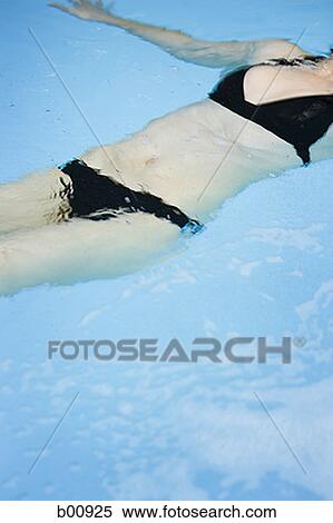 Mid section view of a young woman floating on her back View Large Photo Image Stock Photography - Mid section view of a young woman floating on her back. Fotosearch