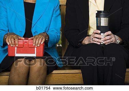 Mid section view of two businesswomen sitting on a bench View Large Photo Image Picture - Mid section view of two businesswomen sitting on a bench. Fotosearch