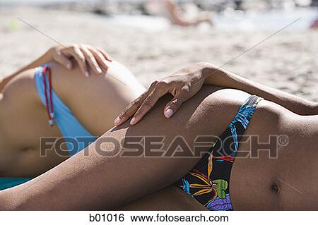 Mid section view of two young women sunbathing on the beach View Large Photo Image Stock Photograph - Mid section view of two young women sunbathing on the beach. Fotosearch
