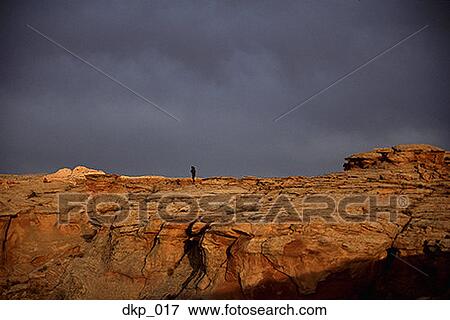 Stock Photo - Person standing on a rock formation. Fotosearch