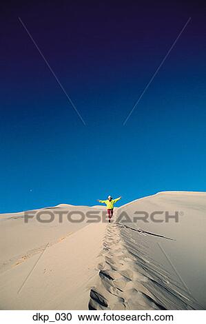 Person walking on a sand dune View Large Photo Image Stock Image - Person walking on a sand dune. Fotosearch