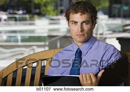 Portrait of a businessman holding a file View Large Photo Image Stock Photo - Portrait of a businessman holding a file. Fotosearch