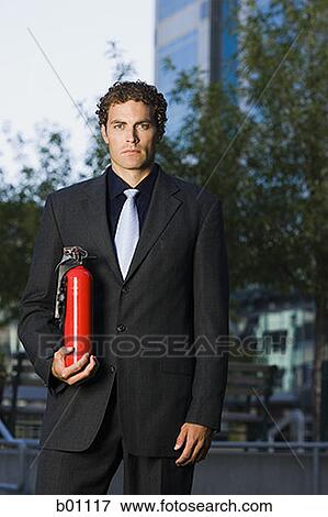 Stock Photo - Portrait of a businessman holding a fire extinguisher. Fotosearch