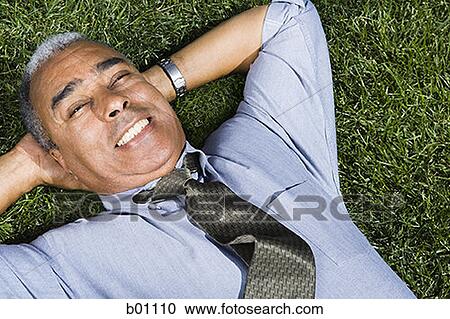 Portrait of a businessman lying on a lawn View Large Photo Image Stock Image - Portrait of a businessman lying on a lawn. Fotosearch