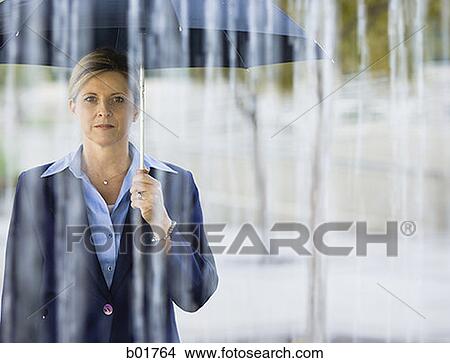 Portrait of a businesswoman holding an umbrella in the rain View Large Photo Image Picture - Portrait of a businesswoman holding an umbrella in the rain. Fotosearch