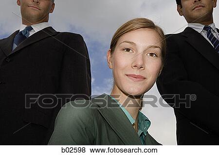 Portrait of a businesswoman with two businessmen standing behind her View Large Photo Image Stock Photo - Portrait of a businesswoman with two businessmen standing behind her. Fotosearch