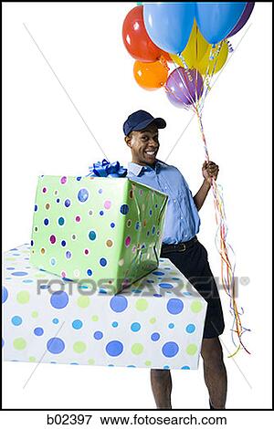 Portrait of a delivery man holding gifts and balloons View Large Photo Image Stock Photo - Portrait of a delivery man holding gifts and balloons. Fotosearch