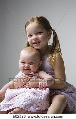 Portrait of a girl holding a baby girl View Large Photo Image Stock Photograph - Portrait of a girl holding a baby girl. Fotosearch