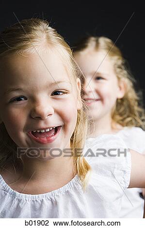 Portrait of a girl smiling with her sister standing behind her View Large Photo Image Stock Image - Portrait of a girl smiling with her sister standing behind her. Fotosearch