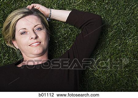 Portrait of a mature woman lying on a lawn View Large Photo Image Stock Image - Portrait of a mature woman lying on a lawn. Fotosearch