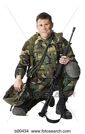 Portrait of a soldier crouching and holding a rifle and a helmet View Large Photo Image Picture - Portrait of a soldier crouching and holding a rifle and a helmet. Fotosearch
