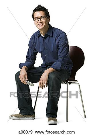 Portrait of a young Asian man sitting on a chair View Large Photo Image Stock Photo - Portrait of a young Asian man sitting on a chair. Fotosearch