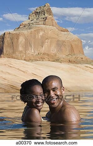 Stock Image - Portrait of a young couple standing in a lake. Fotosearch