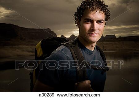 Portrait of a young man carrying a backpack View Large Photo Image Stock Photo - Portrait of a young man carrying a backpack. Fotosearch
