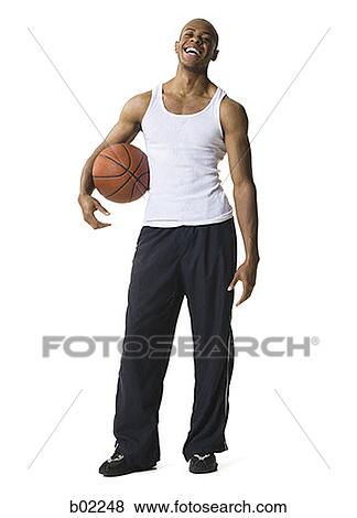 Stock Photo - Portrait of a young man holding a basketball. Fotosearch