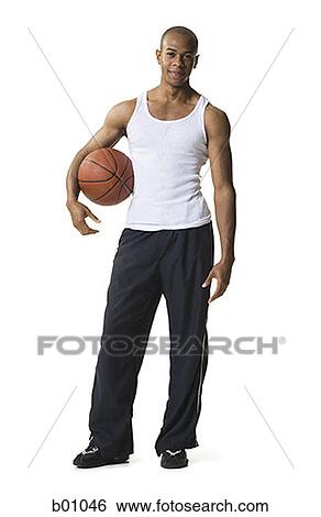 Stock Photograph - Portrait of a young man holding a basketball under his arm. Fotosearch