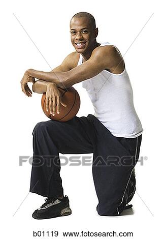 Portrait of a young man kneeling with a basketball View Large Photo Image Stock Photo - Portrait of a young man kneeling with a basketball. Fotosearch