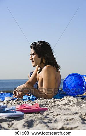 Portrait of a young man lying on the beach View Large Photo Image Stock Photo - Portrait of a young man lying on the beach. Fotosearch