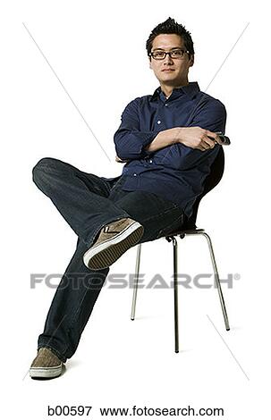 Portrait of a young man sitting on a chair View Large Photo Image Stock Photo - Portrait of a young man sitting on a chair. Fotosearch