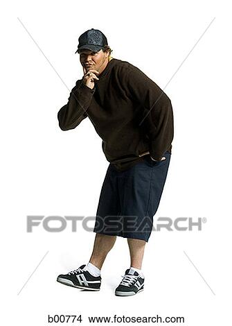 Portrait of a young man standing with his hand on his chin View Large Photo Image Picture - Portrait of a young man standing with his hand on his chin. Fotosearch