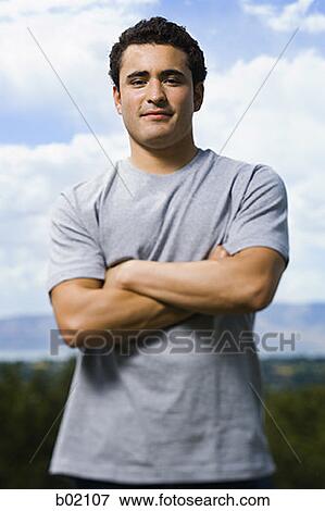 Portrait of a young man standing with his arms folded View Large Photo Image Stock Photo - Portrait of a young man standing with his arms folded. Fotosearch