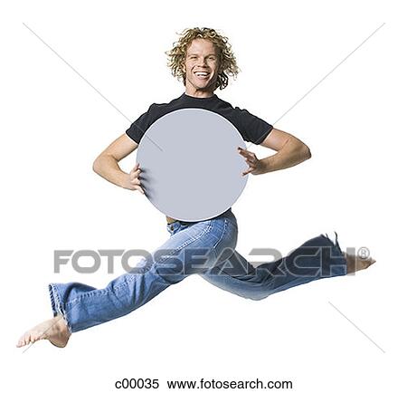 Stock Photography - Portrait of a young man stretching his legs and holding a blank sign. Fotosearch
