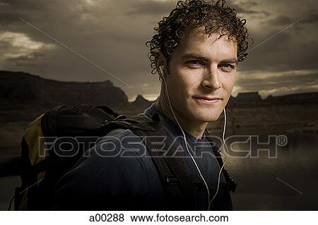 Portrait of a young man wearing headphones and carrying a backpack View Large Photo Image Stock Photo - Portrait of a young man wearing headphones and carrying a backpack. Fotosearch
