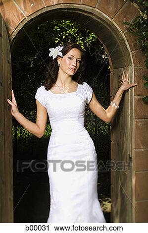 Stock Image - Portrait of a young modern bride standing at the doorway. Fotosearch