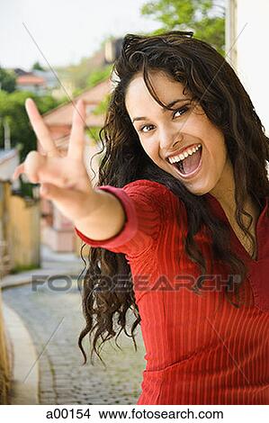 Picture - Portrait of a young woman giving a peace sign. Fotosearch