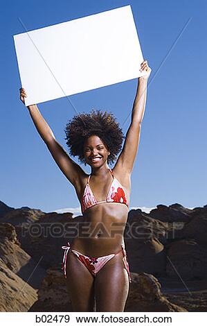 Portrait of a young woman holding up a blank sign View Large Photo Image Stock Photo - Portrait of a young woman holding up a blank sign. Fotosearch