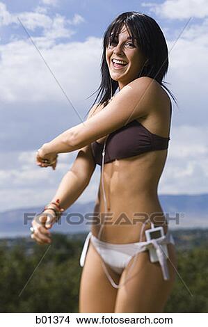 Portrait of a young woman in a bikini listening to an MP3 Player View Large Photo Image Picture - Portrait of a young woman in a bikini listening to an MP3 Player. Fotosearch