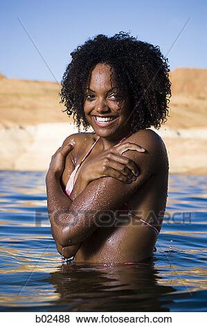 Stock Photo - Portrait of a young woman in a lake, smiling. Fotosearch