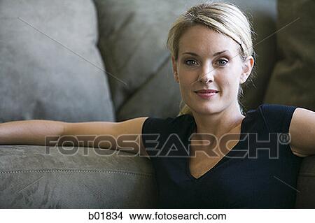 Portrait of a young woman leaning on a couch View Large Photo Image Picture - Portrait of a young woman leaning on a couch. Fotosearch