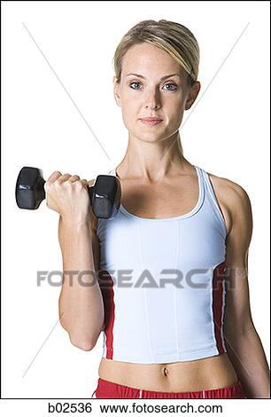 Stock Photograph - Portrait of a young woman picking up a dumbbell. Fotosearch