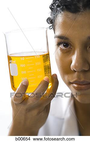 Portrait of a young woman showing a measuring beaker with liquid View Large Photo Image Picture - Portrait of a young woman showing a measuring beaker with liquid. Fotosearch