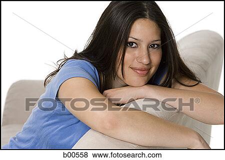 Stock Photo - Portrait of a young woman sitting on a couch. Fotosearch