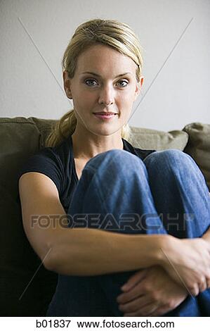 Portrait of a young woman sitting on a couch View Large Photo Image Stock Photo - Portrait of a young woman sitting on a couch. Fotosearch